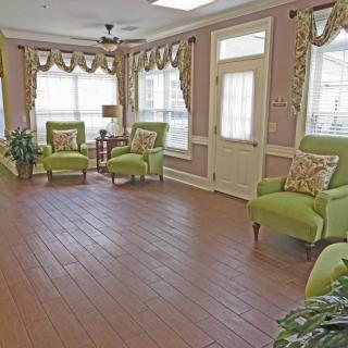 A bright living room with green chairs and large windows.
