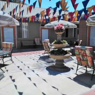 A sunny patio with a central fountain, surrounded by outdoor seating and vibrant flags hanging above.