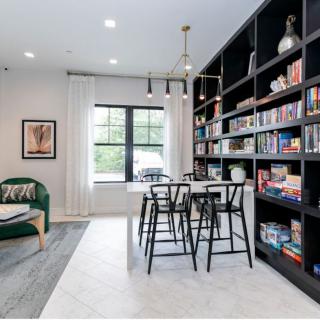A modern living room with a large bookshelf and a seating area, featuring stylish furniture and decor.