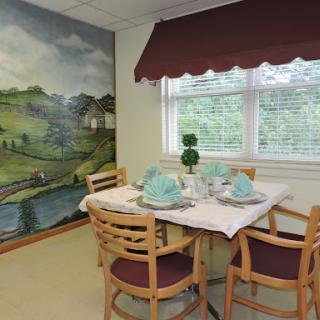 A cozy dining area featuring a beautifully set table with a scenic mural in the background.