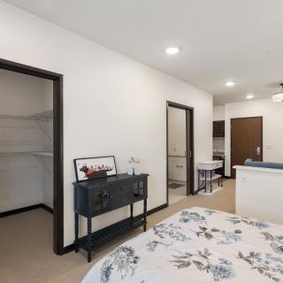 A modern bedroom with a walk-in closet and floral bedding, featuring minimalistic decor.