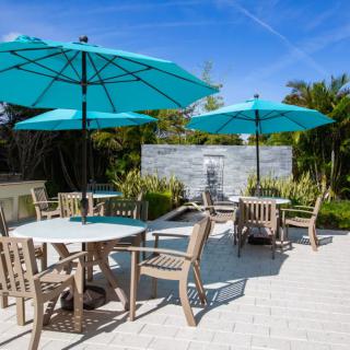 A sunny patio area with tables, chairs, and blue umbrellas.