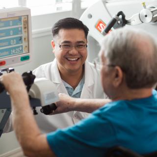 A therapist assists a patient using exercise equipment during a therapy session.