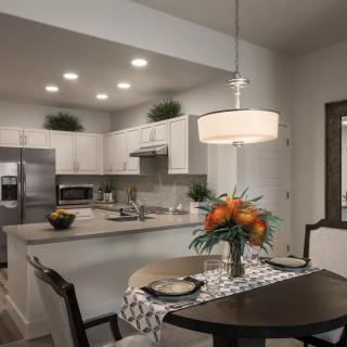 A modern kitchen with sleek stainless steel appliances and a cozy dining area featuring a stylish pendant light.