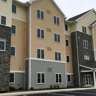 A modern multi-story residential building with a mix of siding materials and multiple windows.