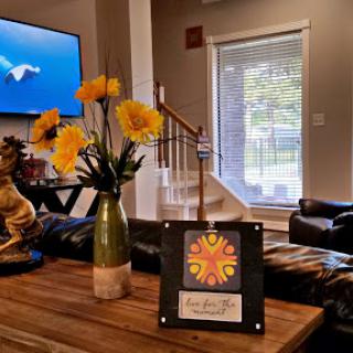 A cozy living room setup featuring a vase of yellow flowers and a decorative piece on a wooden table, with a television in the background.