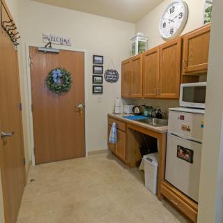 A cozy kitchen with wooden cabinets, a microwave, and refrigerator adorned with decor.