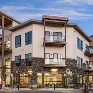 A modern residential apartment building featuring balconies and large windows.