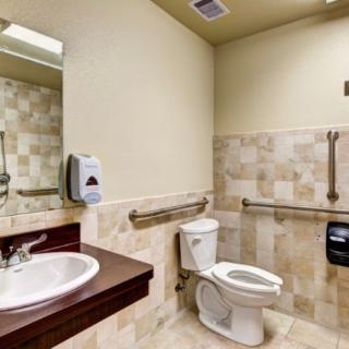 Accessible bathroom with tiled walls and handrails.