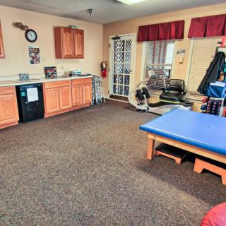 A well-equipped physical therapy room with various exercise equipment and a treatment table.