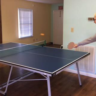 A ping pong table set up in a room with a mural of a player on the wall.