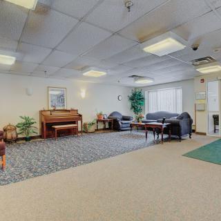 A spacious lobby with a piano, seating area, and indoor plants.