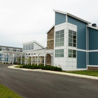 A modern building with a sleek design featuring large glass windows and a paved entrance.
