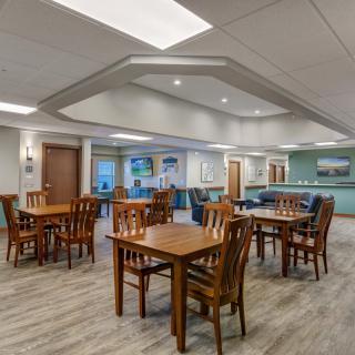 A modern dining area with wooden tables and chairs, featuring contemporary lighting and decor.