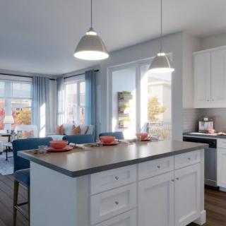 A modern kitchen with white cabinets and a central island, featuring a bright dining area with ample natural light.