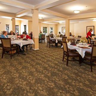 A spacious dining room with tables and chairs, where people are enjoying a meal.