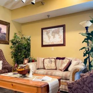 A cozy living room with a sofa, decorative pillows, and plants, featuring a map and artwork on the walls.