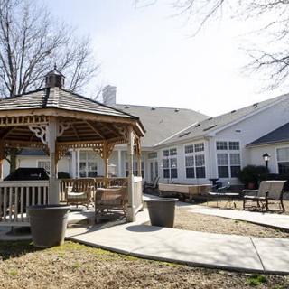 A backyard with a gazebo and patio seating in a sunny residential area.