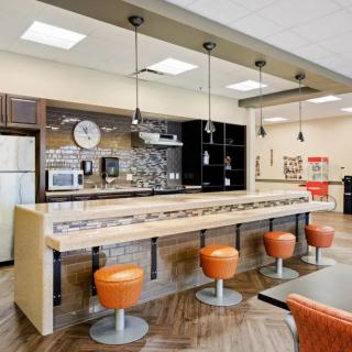 A modern kitchen with a bar area, featuring stylish pendant lighting and orange stools.