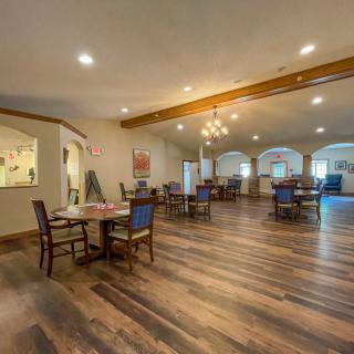 A spacious and elegant dining room with wooden floors and neatly arranged tables and chairs.