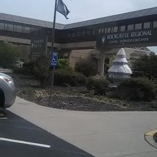 View of a modern building with a flag and landscaped surroundings.