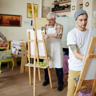 A painting class in progress, featuring an older artist and a younger student focusing on their canvases.