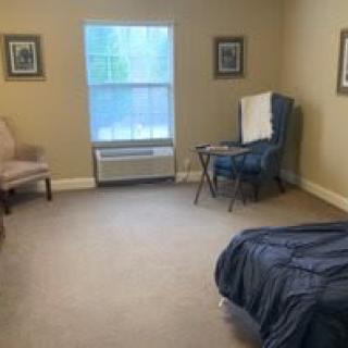 A minimalist bedroom with a bed, chair, and window.