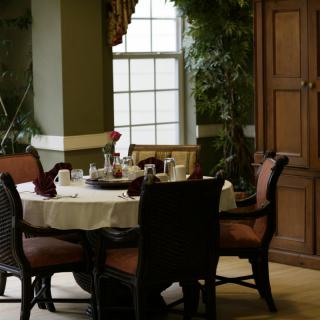 A cozy dining area with a round table set for breakfast, surrounded by chairs and natural light from the window.