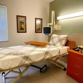 A well-lit hospital patient room featuring a bed and bedside furniture.