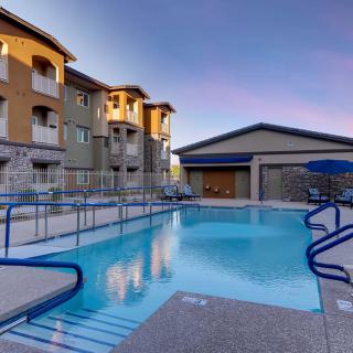 A serene view of an apartment complex with a swimming pool at sunset.