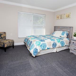 A cozy bedroom with a patterned bedspread and carpeted flooring.