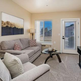 A cozy living room with a comfortable sofa, glass coffee table, lamp, and artwork on the wall.