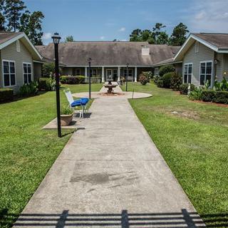 A serene garden pathway flanked by benches and lamp posts, leading to residential buildings.