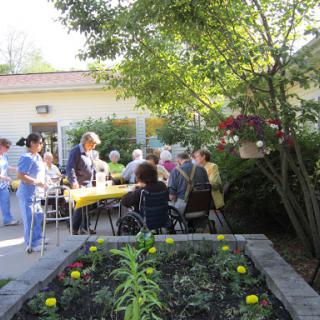 A lively outdoor community event with seniors engaging in activities near a garden.