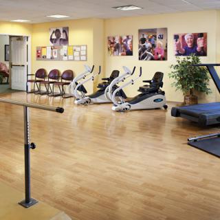 A rehabilitation room equipped with exercise machines and parallel bars for physical therapy.