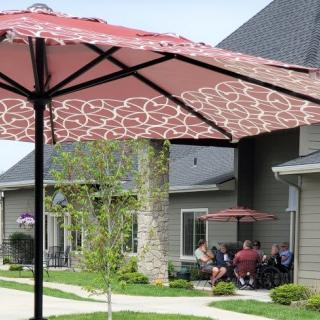 A group of people sitting under a patio umbrella in front of a building.