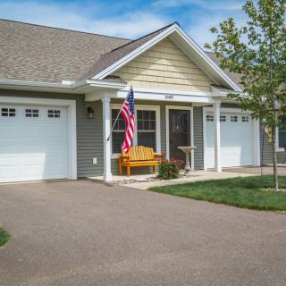 A suburban house with a garage and American flag displayed in the front yard.