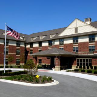 A brick building with an American flag at the entrance under a clear blue sky.