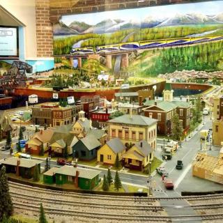 A detailed model train setup depicting a miniature town with tracks, buildings, and landscape scenery.