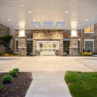 A modern building entrance with stone walls and a covered driveway.