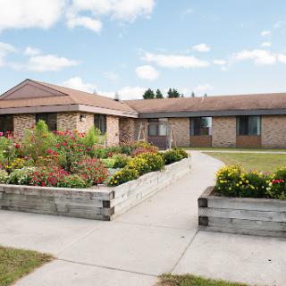 A charming brick building surrounded by a vibrant garden and a well-maintained pathway.