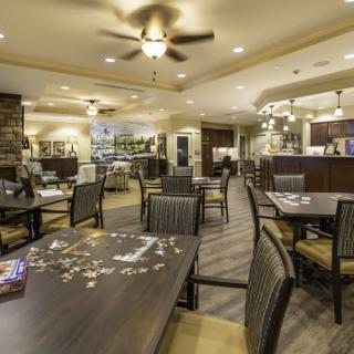 A cozy dining area with tables, chairs, and a puzzle in progress on one table.