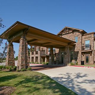 A stone building with a covered entrance and landscaped grounds.