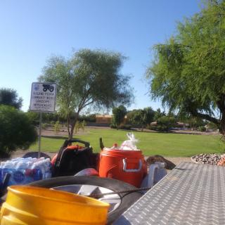 A view of a park with various equipment in the foreground and trees under a clear blue sky.