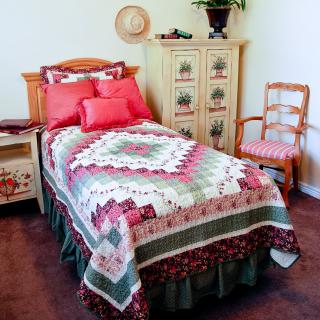 A cozy bedroom with a single bed featuring a colorful quilt, surrounded by rustic furniture and warm decor.