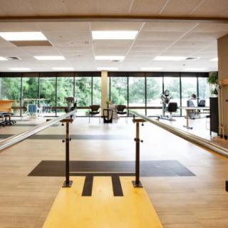 A spacious physical therapy and rehabilitation center equipped with parallel bars and other exercise equipment.