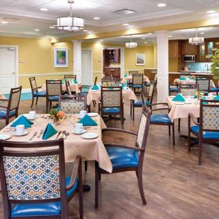 A well-decorated dining room with multiple tables and chairs, featuring elegant light fixtures.