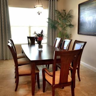 A well-decorated dining room with a wooden table and chairs, featuring a potted plant by the window.