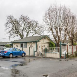 A small residential building with a car parked in front on an overcast day.