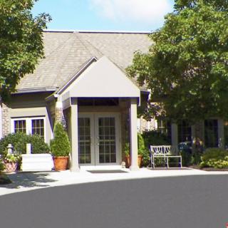 A building entrance surrounded by trees and outdoor seating.
